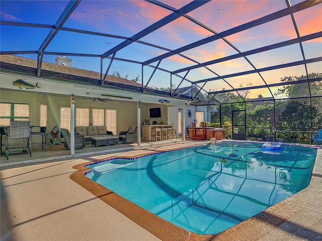 view of pool with a patio, ceiling fan, glass enclosure, and an outdoor living space