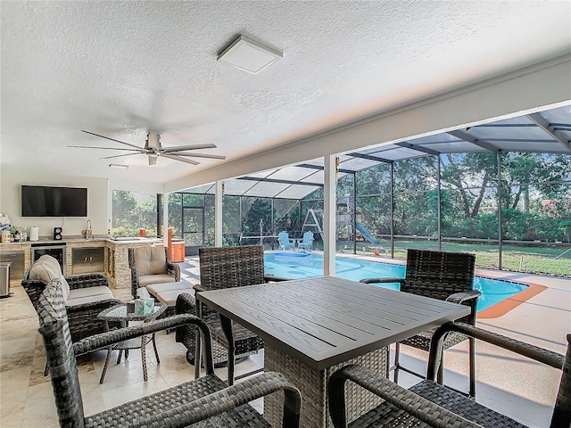 sunroom / solarium featuring ceiling fan, sink, and a pool