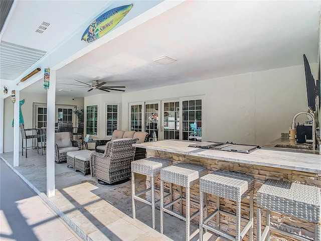 view of patio / terrace with an outdoor wet bar, ceiling fan, french doors, and an outdoor living space