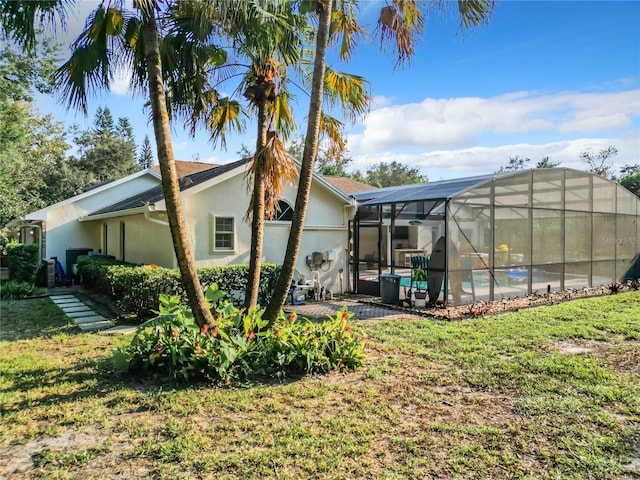 rear view of property featuring a patio area, a yard, a swimming pool, and glass enclosure