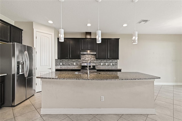 kitchen with sink, appliances with stainless steel finishes, pendant lighting, and an island with sink