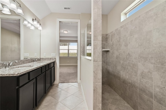 bathroom with vanity, tiled shower, tile patterned floors, and vaulted ceiling