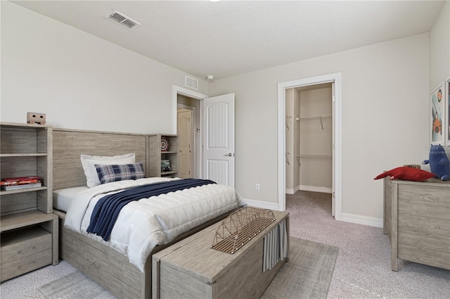 carpeted bedroom with a walk in closet and a closet