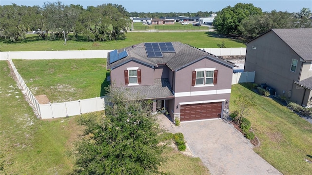 view of front of home with a garage, a front lawn, and solar panels