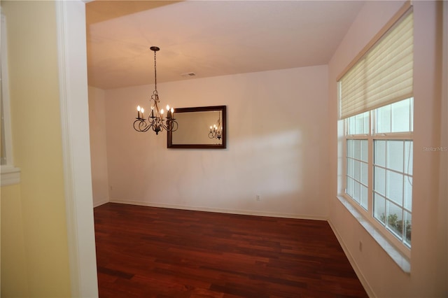 unfurnished room with an inviting chandelier and dark hardwood / wood-style flooring