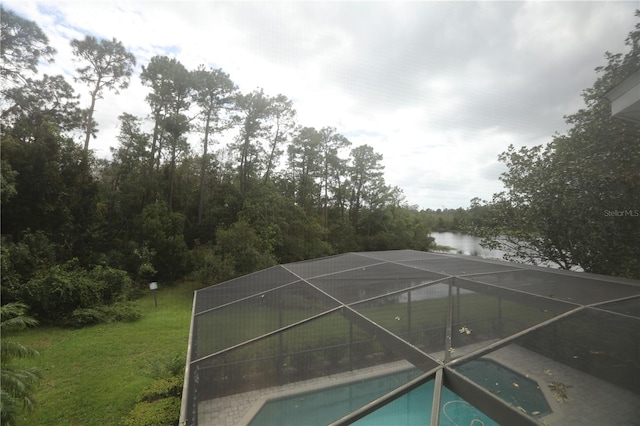 view of swimming pool featuring a water view, a lanai, and a lawn