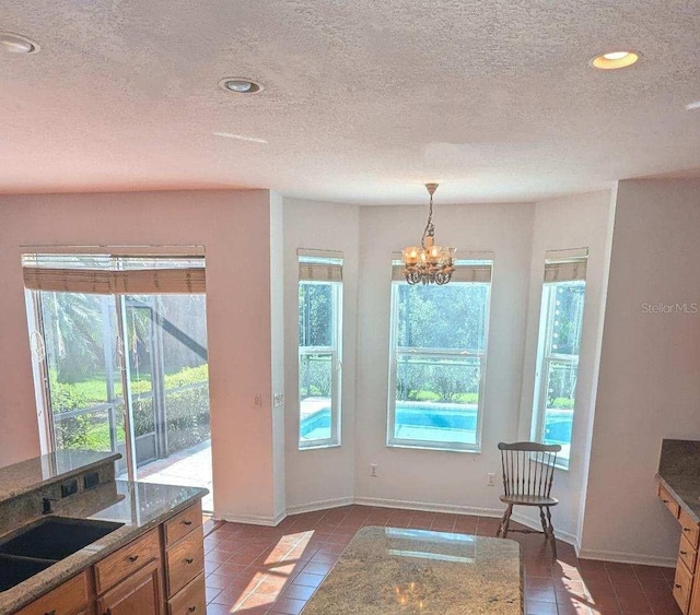 doorway with a textured ceiling, light tile patterned flooring, and a chandelier