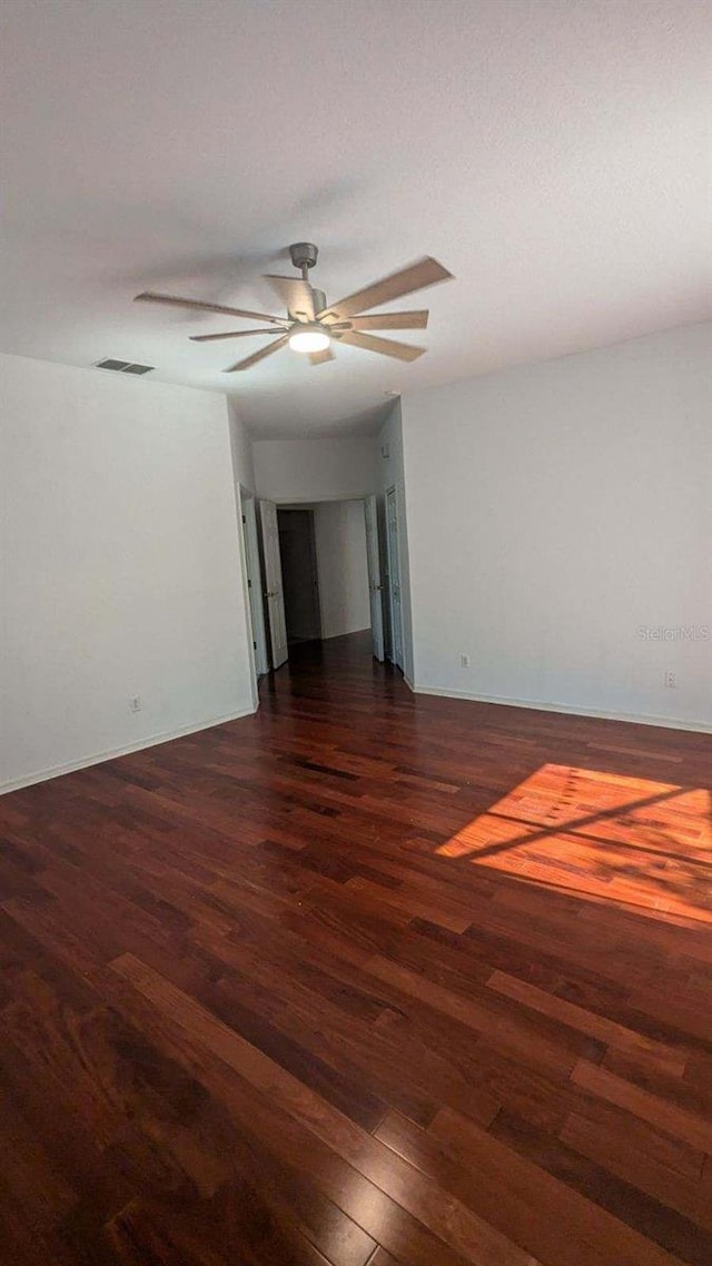 empty room with dark wood-type flooring and ceiling fan