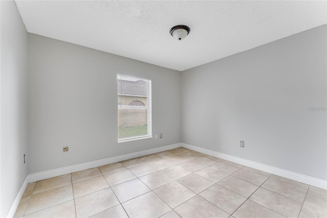 tiled spare room featuring a textured ceiling