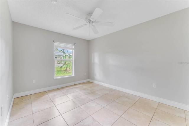 empty room with ceiling fan, a textured ceiling, and light tile patterned floors