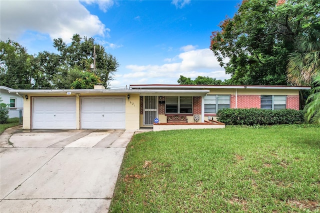 single story home with covered porch, a front yard, and a garage