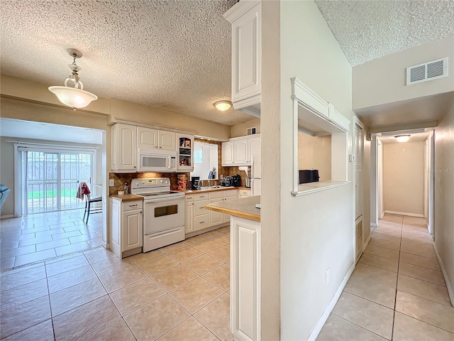 kitchen with white appliances, a textured ceiling, light tile patterned floors, decorative light fixtures, and white cabinetry