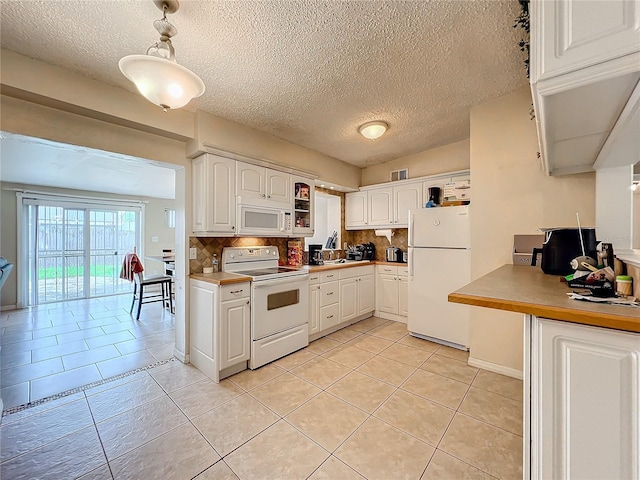 kitchen with backsplash, white appliances, light tile patterned floors, white cabinets, and hanging light fixtures