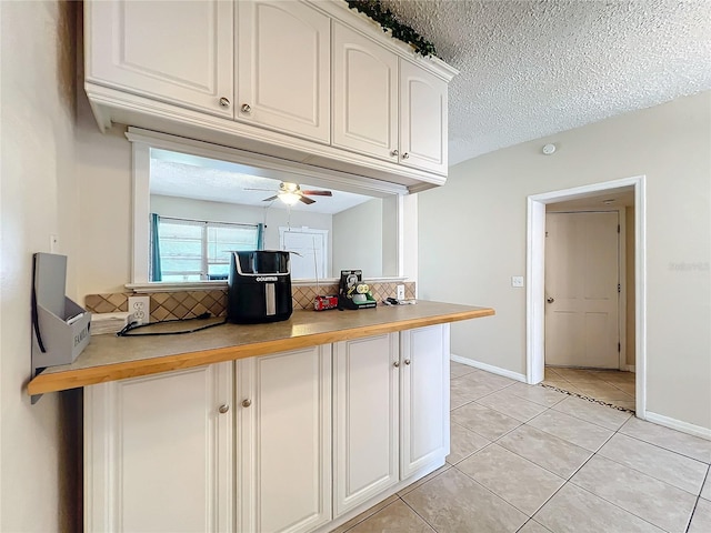 kitchen featuring kitchen peninsula, light tile patterned floors, a textured ceiling, and ceiling fan