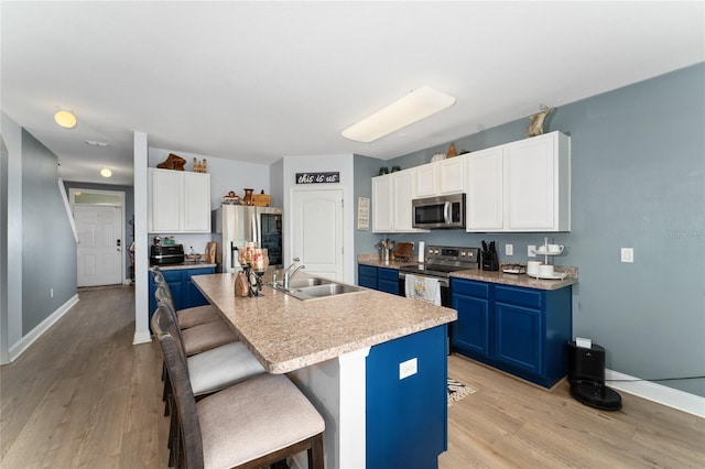 kitchen with blue cabinetry, sink, stainless steel appliances, an island with sink, and a kitchen bar