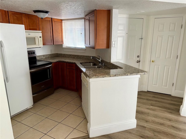 kitchen with light hardwood / wood-style flooring, a textured ceiling, sink, and white appliances