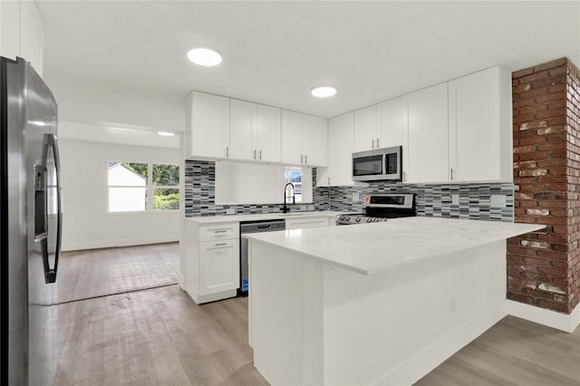 1004 Jersey St, Cocoa, FL 32927 - kitchen featuring appliances with stainless steel finishes, a peninsula, light wood-style flooring, light countertops, and white cabinets