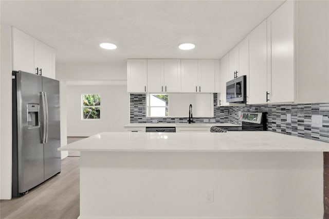 kitchen featuring white cabinets, stainless steel appliances, and light wood-type flooring