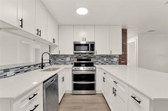 kitchen featuring white cabinets, appliances with stainless steel finishes, sink, and kitchen peninsula