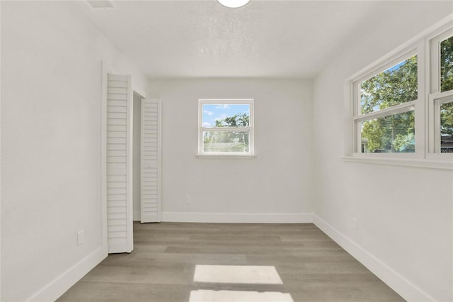 unfurnished bedroom featuring a textured ceiling, light wood-type flooring, and multiple windows