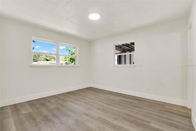 unfurnished room with light hardwood / wood-style flooring and a textured ceiling