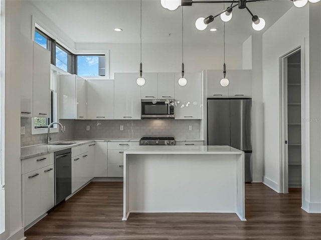 kitchen featuring white cabinets, sink, a kitchen island, decorative light fixtures, and appliances with stainless steel finishes