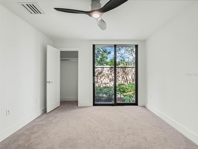 unfurnished bedroom with a closet, light colored carpet, and ceiling fan