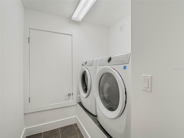 laundry area featuring dark tile patterned floors and washer and clothes dryer