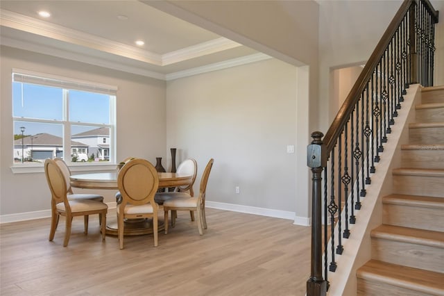 dining room featuring light hardwood / wood-style floors, a raised ceiling, and ornamental molding