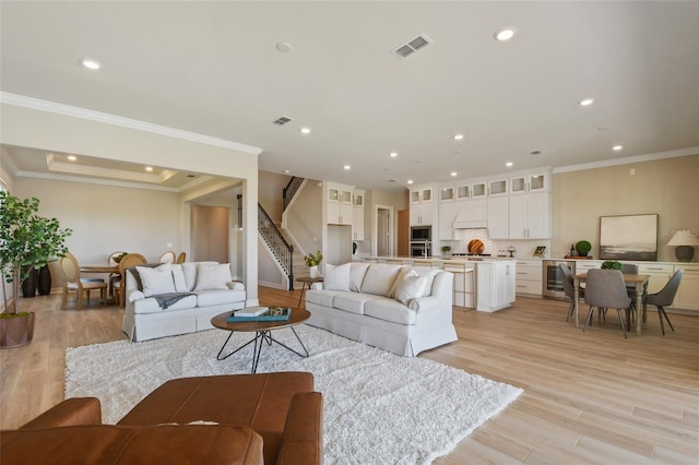 living room with light hardwood / wood-style floors, ornamental molding, and beverage cooler