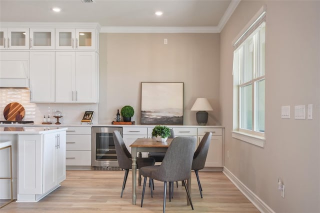 dining room with light hardwood / wood-style flooring, beverage cooler, and crown molding