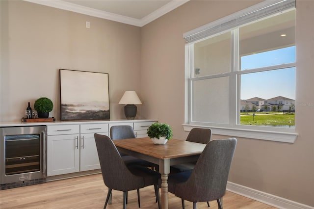 dining room featuring light hardwood / wood-style floors, ornamental molding, and beverage cooler