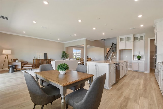 dining space featuring light hardwood / wood-style flooring, sink, and crown molding