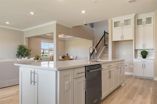 kitchen with a center island with sink, backsplash, white cabinetry, crown molding, and sink