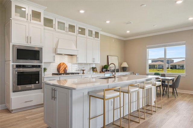 kitchen featuring appliances with stainless steel finishes, a kitchen island with sink, and white cabinetry