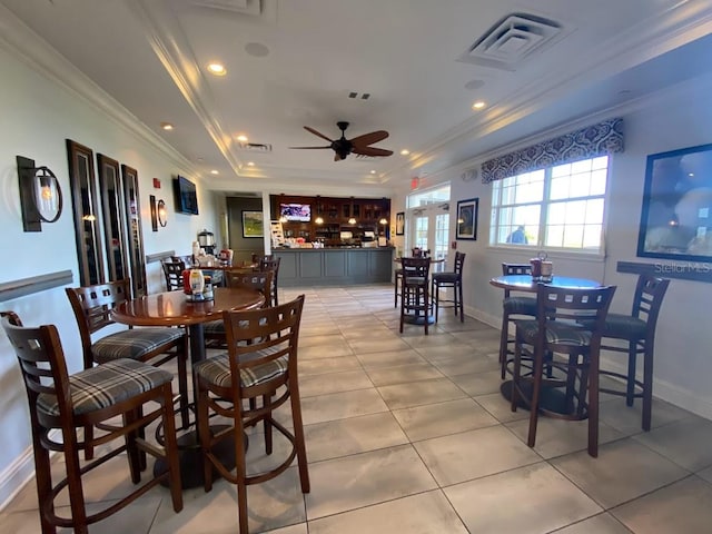 tiled dining area featuring crown molding, a tray ceiling, and ceiling fan