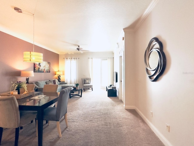 carpeted dining area with crown molding and ceiling fan