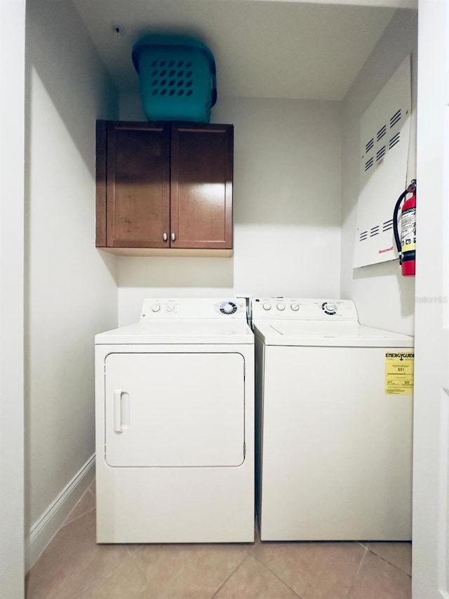 washroom with washer and dryer, cabinets, and light tile patterned floors