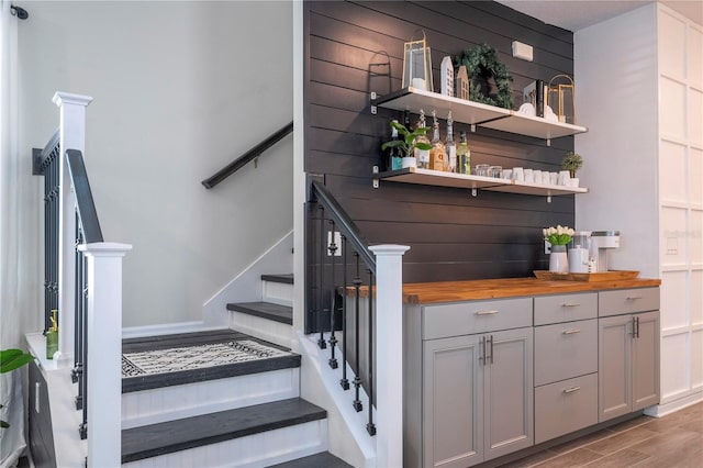 bar with light hardwood / wood-style flooring, butcher block counters, and gray cabinetry