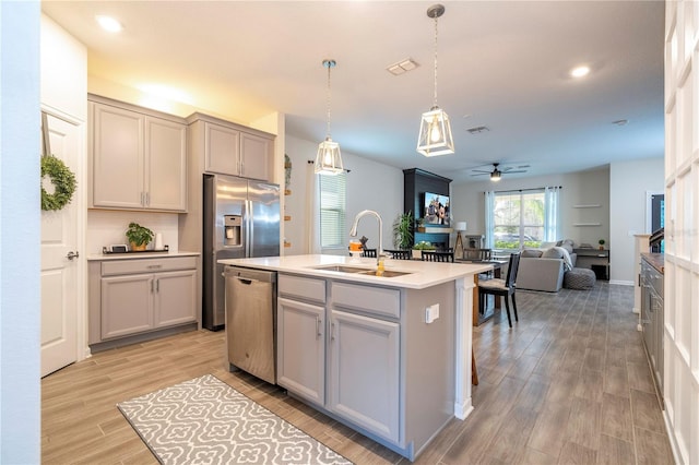 kitchen featuring gray cabinets, a kitchen island with sink, ceiling fan, light hardwood / wood-style flooring, and stainless steel dishwasher