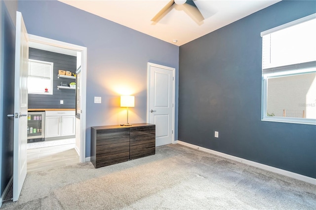 carpeted bedroom with ceiling fan, beverage cooler, and multiple windows