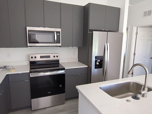 kitchen featuring gray cabinets, sink, appliances with stainless steel finishes, and light hardwood / wood-style flooring