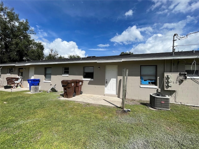 back of property with cooling unit, a lawn, and a patio area