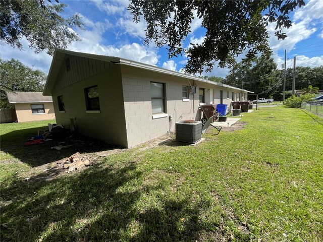 view of side of property featuring central AC unit and a lawn