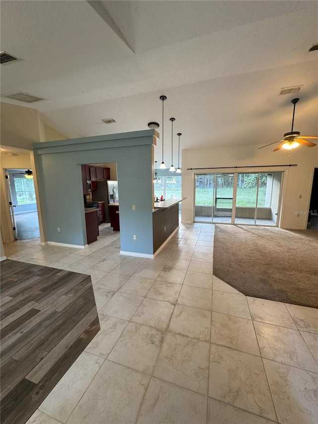 interior space featuring ceiling fan, baseboards, lofted ceiling, and visible vents