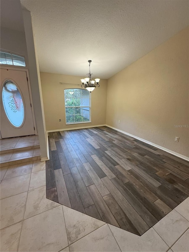 unfurnished dining area with hardwood / wood-style floors, a notable chandelier, and a textured ceiling