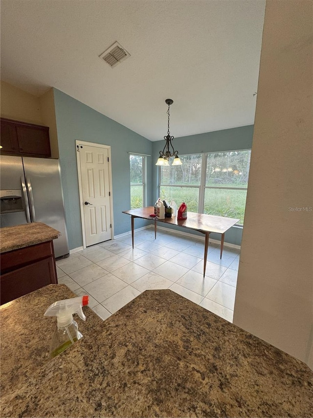 dining area with lofted ceiling, visible vents, light tile patterned floors, baseboards, and a chandelier