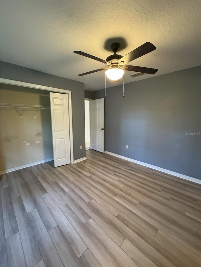 unfurnished bedroom featuring ceiling fan, a textured ceiling, light hardwood / wood-style flooring, and a closet