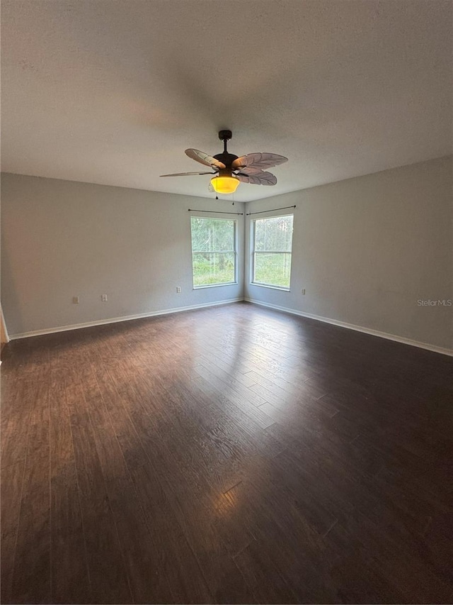 spare room with a ceiling fan, baseboards, a textured ceiling, and dark wood-type flooring
