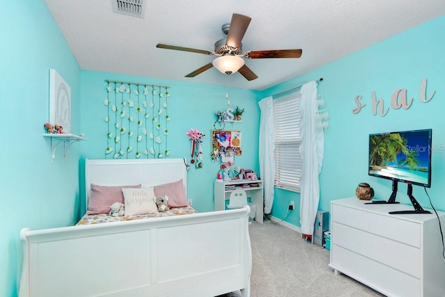 bedroom with ceiling fan, light colored carpet, and a textured ceiling